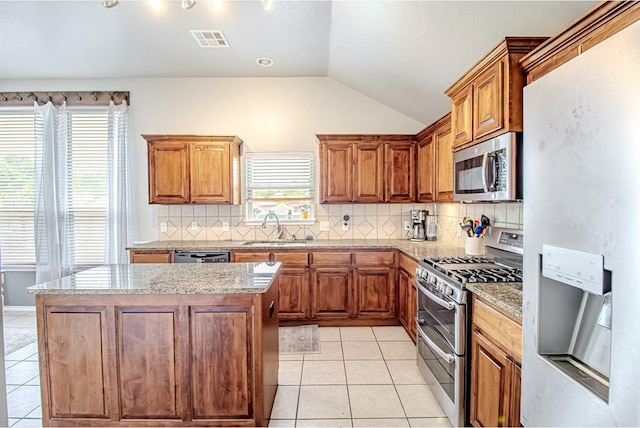 708 Ashwood Ln, Moore, OK 73160 - kitchen with appliances with stainless steel finishes, a sink, lofted ceiling, light tile patterned floors, and brown cabinetry