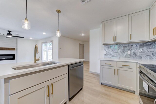 737 NW 89th St, Oklahoma City, OK 73114 - kitchen featuring appliances with stainless steel finishes, a sink, backsplash, pendant lighting, and light wood-style floors