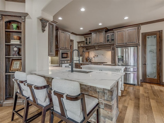 4401 Cannon Dr, Norman, OK 73072 - kitchen featuring appliances with stainless steel finishes, ornamental molding, a peninsula, light wood finished floors, and glass insert cabinets