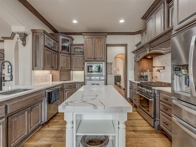 4401 Cannon Dr, Norman, OK 73072 - kitchen with appliances with stainless steel finishes, ornamental molding, light wood-type flooring, arched walkways, and backsplash