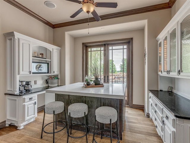 4401 Cannon Dr, Norman, OK 73072 - kitchen with white cabinetry, light wood-style flooring, ornamental molding, a breakfast bar, and ceiling fan