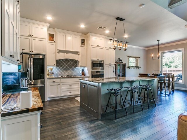 4133 Carmina Dr, Edmond, OK 73034 - kitchen with appliances with stainless steel finishes, a sink, crown molding, tasteful backsplash, and a kitchen bar