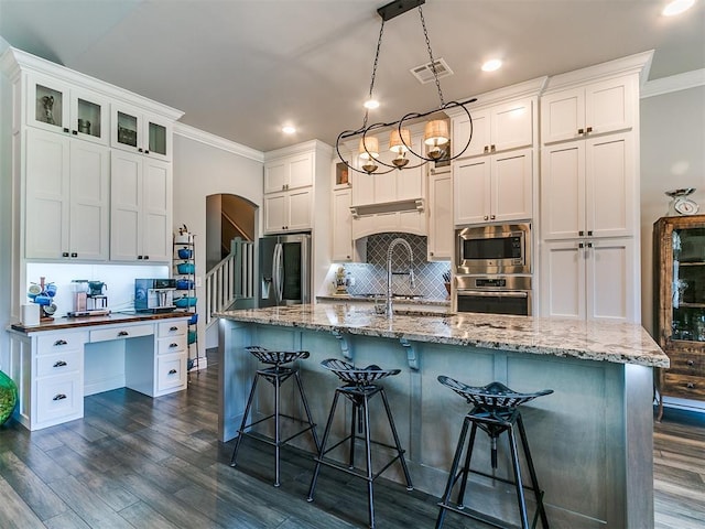 4133 Carmina Dr, Edmond, OK 73034 - kitchen featuring appliances with stainless steel finishes, ornamental molding, backsplash, dark wood-style floors, and a kitchen bar