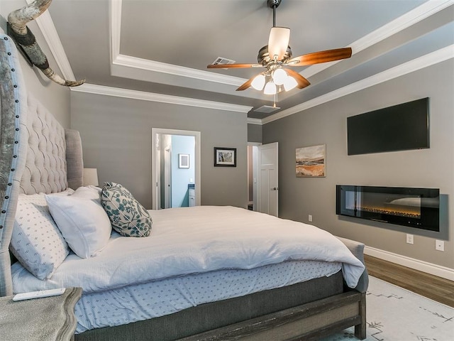 4133 Carmina Dr, Edmond, OK 73034 - bedroom with a tray ceiling, wood finished floors, crown molding, baseboards, and a ceiling fan