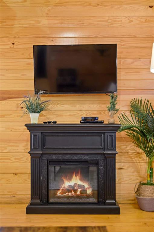 47 Sockeye Rd, Broken Bow, OK 74728 - detailed view of a glass covered fireplace, wood walls, and wood finished floors