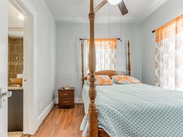 bedroom featuring wood finished floors, connected bathroom, a ceiling fan, and baseboards