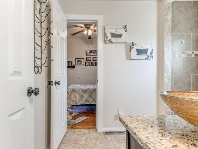 ensuite bathroom featuring a ceiling fan, tile patterned floors, and baseboards