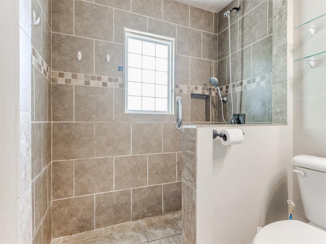bathroom with a tile shower and toilet