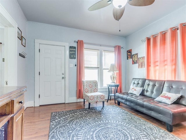 living area with wood finished floors, a ceiling fan, and baseboards