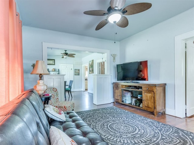 living room with a ceiling fan, wood finished floors, and baseboards