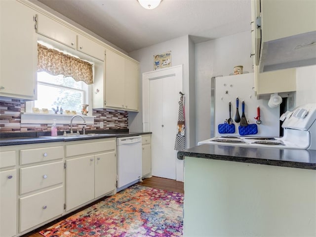 kitchen with white appliances, a sink, tasteful backsplash, dark countertops, and wood finished floors