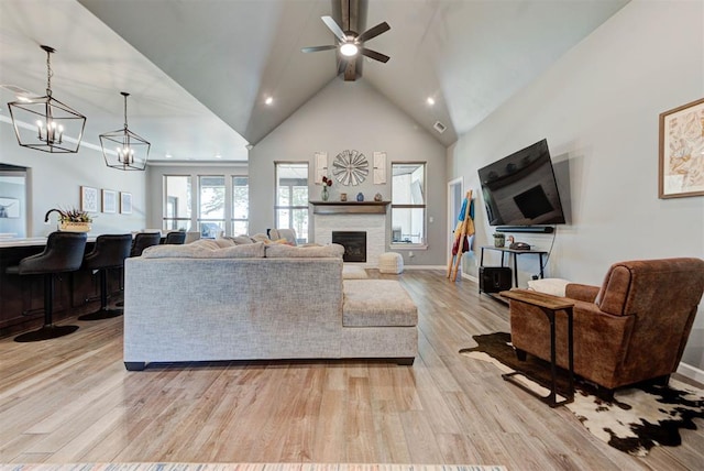 8624 Grey Wind Way, Arcadia, OK 73007 - living room featuring a ceiling fan, light wood-type flooring, a stone fireplace, recessed lighting, and a chandelier