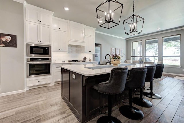 8624 Grey Wind Way, Arcadia, OK 73007 - kitchen featuring oven, light countertops, a kitchen island with sink, built in microwave, and baseboards