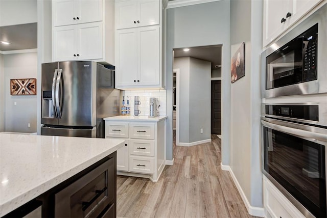 8624 Grey Wind Way, Arcadia, OK 73007 - kitchen with stainless steel appliances, light wood-style floors, baseboards, white cabinetry, and tasteful backsplash
