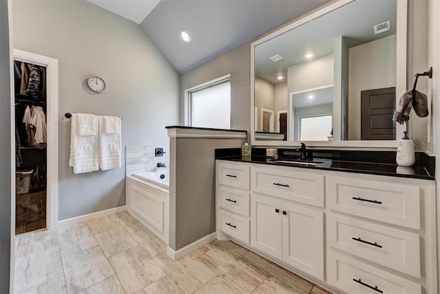 8624 Grey Wind Way, Arcadia, OK 73007 - bathroom featuring lofted ceiling, vanity, a bath, marble look tile flooring, and a walk in closet