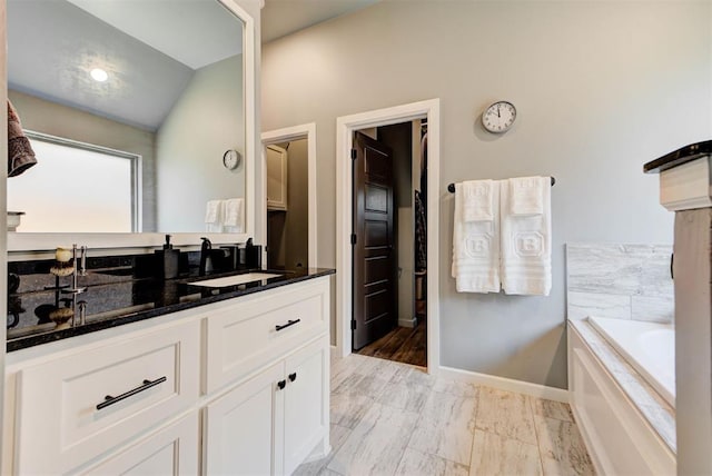 8624 Grey Wind Way, Arcadia, OK 73007 - bathroom with vanity, a garden tub, baseboards, lofted ceiling, and marble look tile flooring