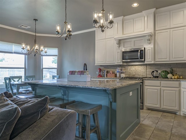 2145 Sycamore Creek Ave, Yukon, OK 73099 - kitchen featuring appliances with stainless steel finishes, a chandelier, backsplash, a kitchen island, and crown molding