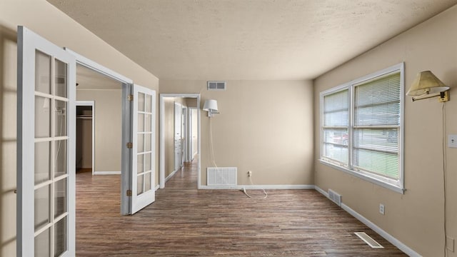 4313 SE 13th St, Oklahoma City, OK 73115 - empty room featuring french doors, dark wood finished floors, a textured ceiling, and baseboards