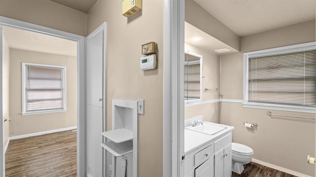 4313 SE 13th St, Oklahoma City, OK 73115 - bathroom featuring wood finished floors, toilet, vanity, and baseboards