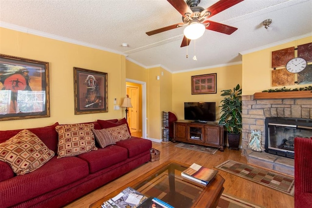 13351 El Zorro, Edmond, OK 73034 - living area with wood finished floors, crown molding, a stone fireplace, ceiling fan, and a textured ceiling