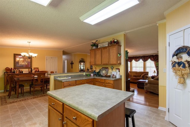 13351 El Zorro, Edmond, OK 73034 - kitchen featuring a textured ceiling, ornamental molding, a chandelier, a peninsula, and brown cabinets