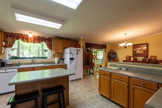 13351 El Zorro, Edmond, OK 73034 - kitchen with white appliances, a textured ceiling, brown cabinetry, a chandelier, and a kitchen bar
