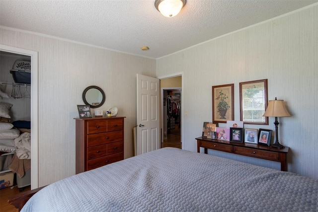 13351 El Zorro, Edmond, OK 73034 - bedroom featuring crown molding, a closet, a textured ceiling, a walk in closet, and wood finished floors