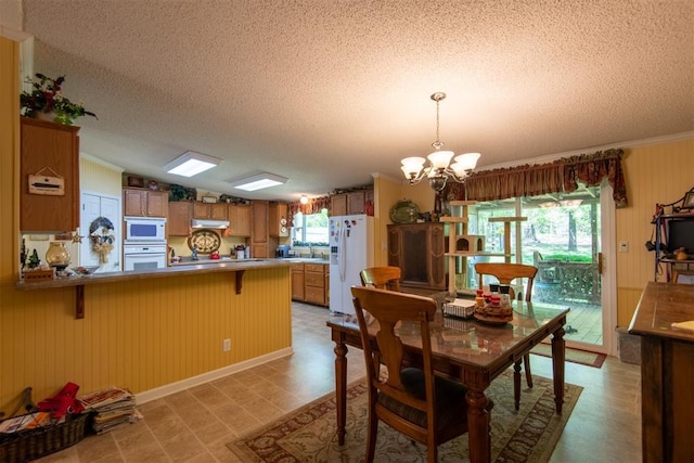 13351 El Zorro, Edmond, OK 73034 - dining area featuring a chandelier, a textured ceiling, vaulted ceiling, wooden walls, and ornamental molding