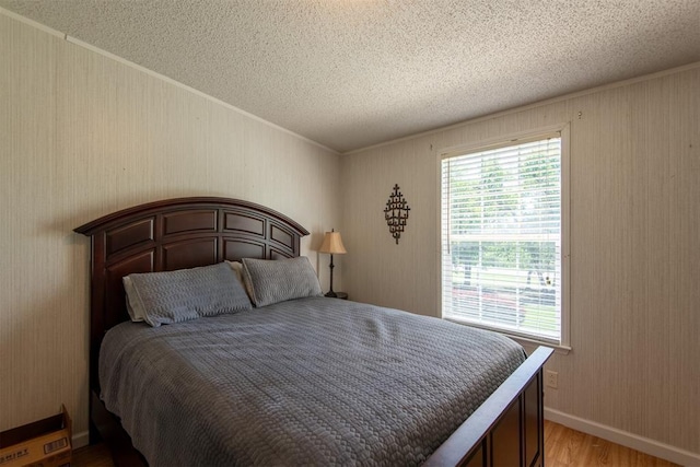 13351 El Zorro, Edmond, OK 73034 - bedroom with a textured ceiling, light wood-style flooring, ornamental molding, and wooden walls