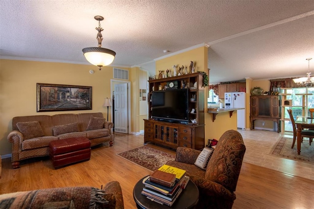 13351 El Zorro, Edmond, OK 73034 - living room featuring a textured ceiling, a chandelier, light wood-style floors, and crown molding