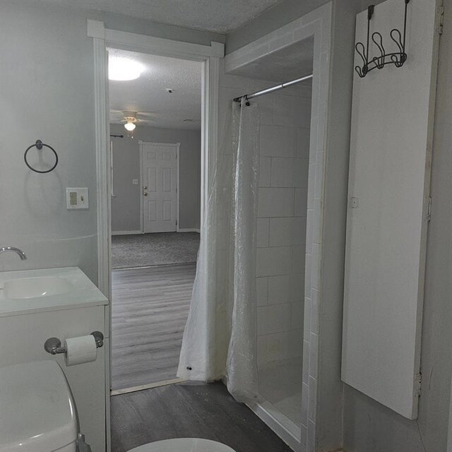 1015 W 10th Ave, Stillwater, OK 74074 - bathroom with a sink, toilet, a stall shower, wood finished floors, and a textured ceiling