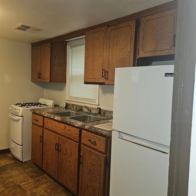 1015 W 10th Ave, Stillwater, OK 74074 - kitchen featuring white appliances, dark countertops, a sink, and brown cabinetry