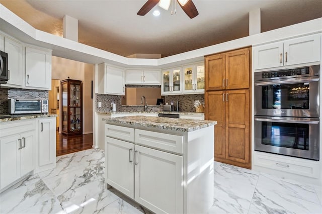 1721 Park View Pl, Edmond, OK 73003 - kitchen with appliances with stainless steel finishes, light marble finish flooring, tasteful backsplash, and glass insert cabinets