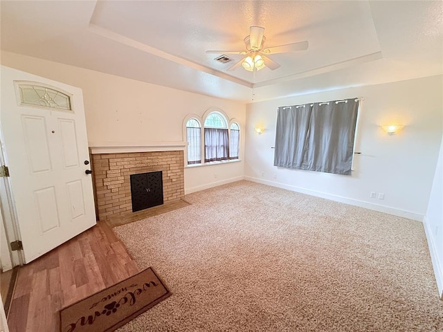 1710 W Chickasha Ave, Chickasha, OK 73018 - unfurnished living room featuring a tray ceiling, a ceiling fan, a fireplace, and baseboards