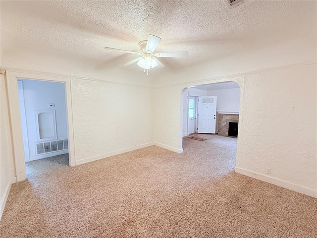 1710 W Chickasha Ave, Chickasha, OK 73018 - spare room with a textured wall, light carpet, a textured ceiling, ceiling fan, and arched walkways