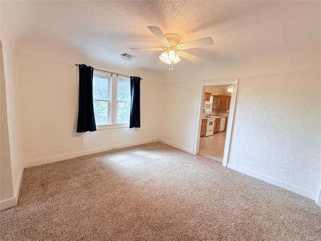1710 W Chickasha Ave, Chickasha, OK 73018 - spare room featuring a textured wall, a textured ceiling, light colored carpet, a ceiling fan, and baseboards