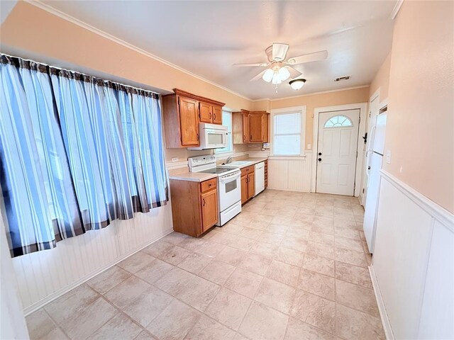 1710 W Chickasha Ave, Chickasha, OK 73018 - kitchen with white appliances, brown cabinetry, ceiling fan, light countertops, and a wainscoted wall