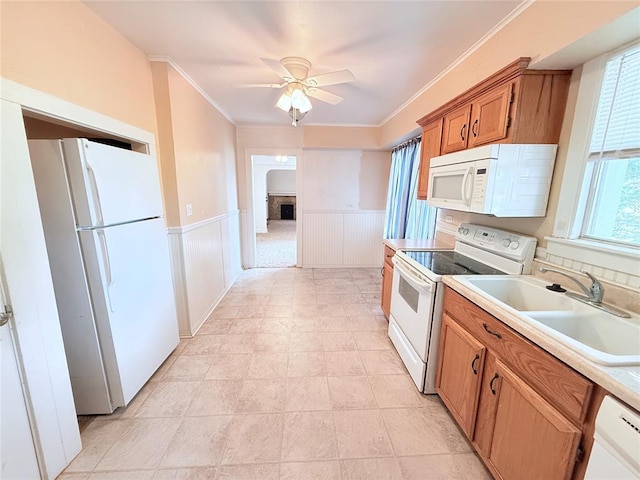 1710 W Chickasha Ave, Chickasha, OK 73018 - kitchen featuring white appliances, a sink, brown cabinetry, a wainscoted wall, and a ceiling fan