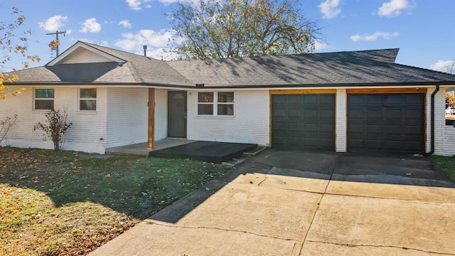 ranch-style home with an attached garage, brick siding, driveway, a front yard, and a shingled roof