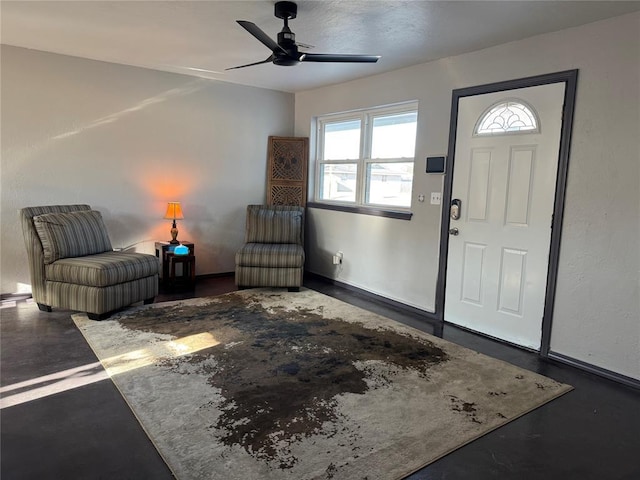 foyer with finished concrete floors, ceiling fan, and baseboards
