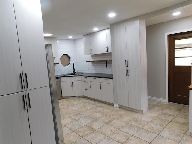 5737 NW 31st St, Oklahoma City, OK 73122 - kitchen featuring a sink, dark countertops, backsplash, recessed lighting, and white cabinetry