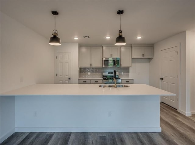 1021 NE 18th St, Oklahoma City, OK 73111 - kitchen featuring stainless steel appliances, a sink, dark wood finished floors, light countertops, and backsplash