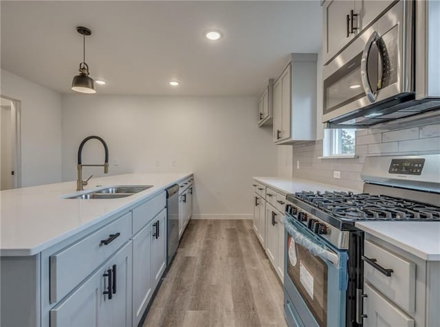 1021 NE 18th St, Oklahoma City, OK 73111 - kitchen with stainless steel appliances, a sink, light countertops, light wood finished floors, and a peninsula