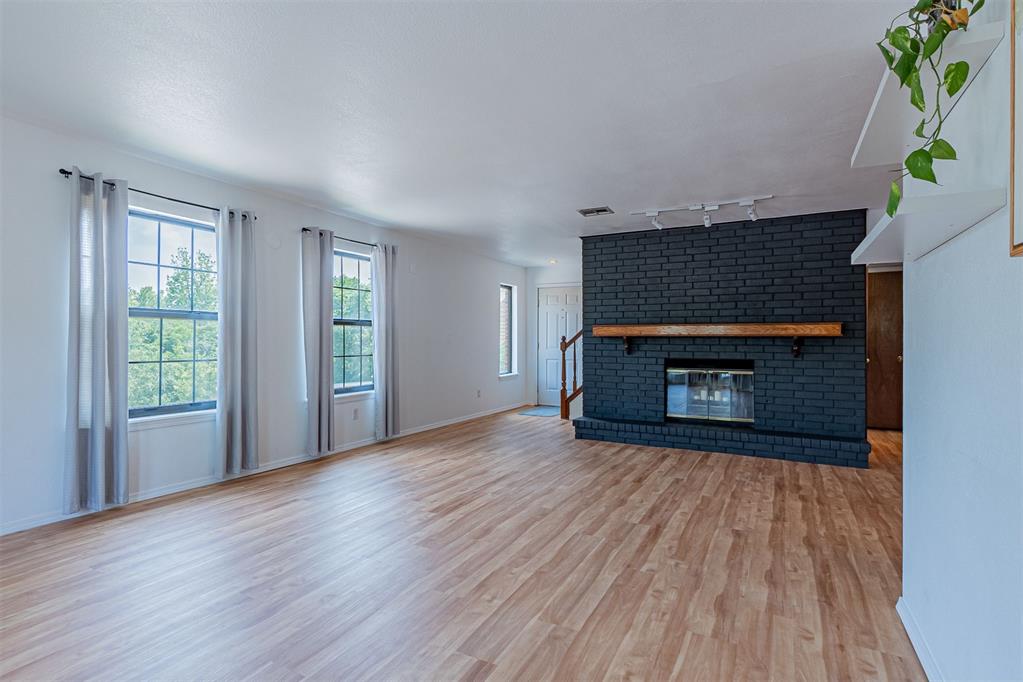 4400 Hemingway Dr Unit 270, Oklahoma City, OK 73118 - unfurnished living room with rail lighting, wood finished floors, a fireplace, and baseboards