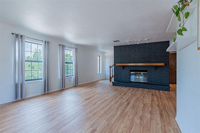 4400 Hemingway Dr Unit 270, Oklahoma City, OK 73118 - unfurnished living room with rail lighting, wood finished floors, a fireplace, and baseboards