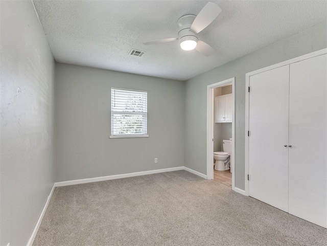 8 Shirley Ln, Edmond, OK 73034 - unfurnished bedroom with carpet, a textured ceiling, connected bathroom, baseboards, and ceiling fan