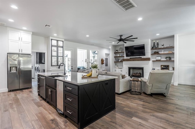 6301 144th Ave NE, Newalla, OK 74857 - kitchen featuring appliances with stainless steel finishes, washing machine and clothes dryer, a fireplace, dark wood-type flooring, and a sink