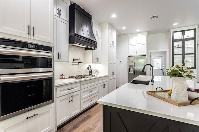 6301 144th Ave NE, Newalla, OK 74857 - kitchen with stainless steel appliances, custom range hood, a sink, wood finished floors, and backsplash