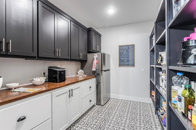 6301 144th Ave NE, Newalla, OK 74857 - kitchen featuring wooden counters, freestanding refrigerator, baseboards, dark cabinets, and white cabinets