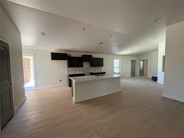 5 Old Glory Ave, Altus, OK 73521 - kitchen featuring light wood-style floors, baseboards, a kitchen island with sink, vaulted ceiling, and recessed lighting